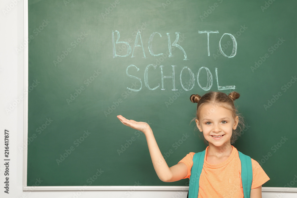 Little child near chalkboard with text BACK TO SCHOOL Little child near chalkboard with text BACK TO SCHOOL