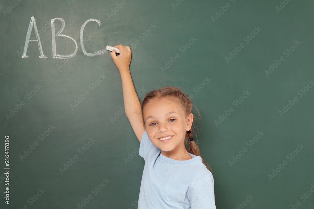Little school child writing with chalk on blackboard Little school child writing with chalk on blackboard