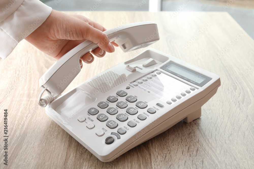Woman using telephone at table indoors, closeup Woman using telephone at table indoors, closeup