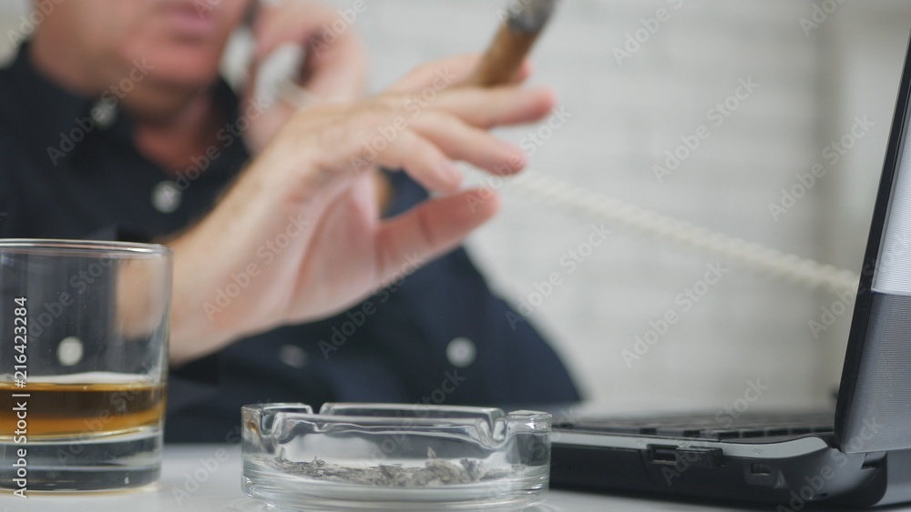 Blurred Image with a Businessman Smoking Cigar Drinking Whisky Using Telephone