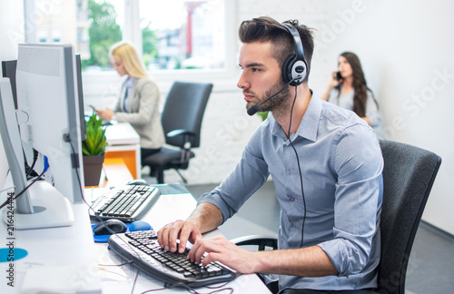 Beautiful handsome man customer service representative working with colleagues in office