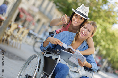 two friends visiting foreign city one sitting in wheelchair