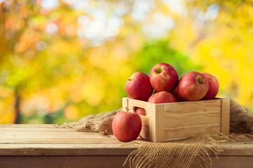 Red apples in wooden box on table