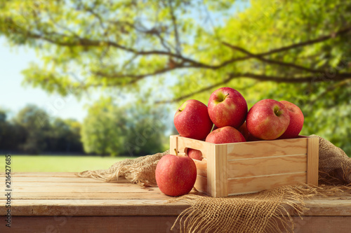 Red apples in wooden box on table