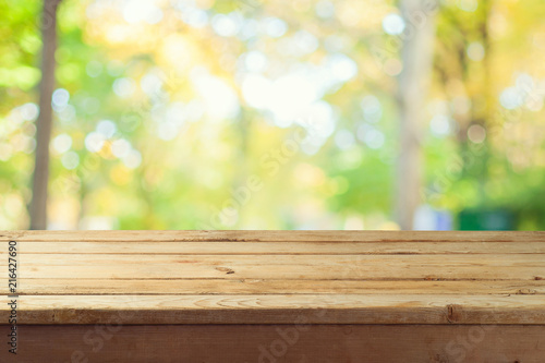 Empty wooden table over autumn nature bokeh background
