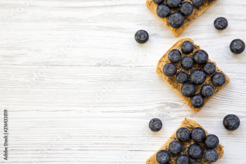Vegan toasts with peanut butter, blueberries and chia seeds on a white wooden background, top view. Healthy eating. Flat lay, from above. Space for text.
