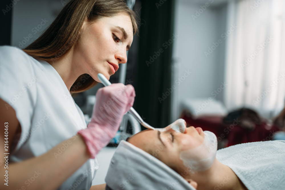 Doctor in gloves rubs the cream on patient face Doctor in gloves rubs the cream on patient face