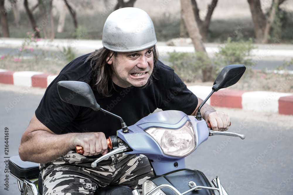 Expressive face of a man on a scooter. Funny man with a helmet riding a  motorcycle. Stock Photo | Adobe Stock