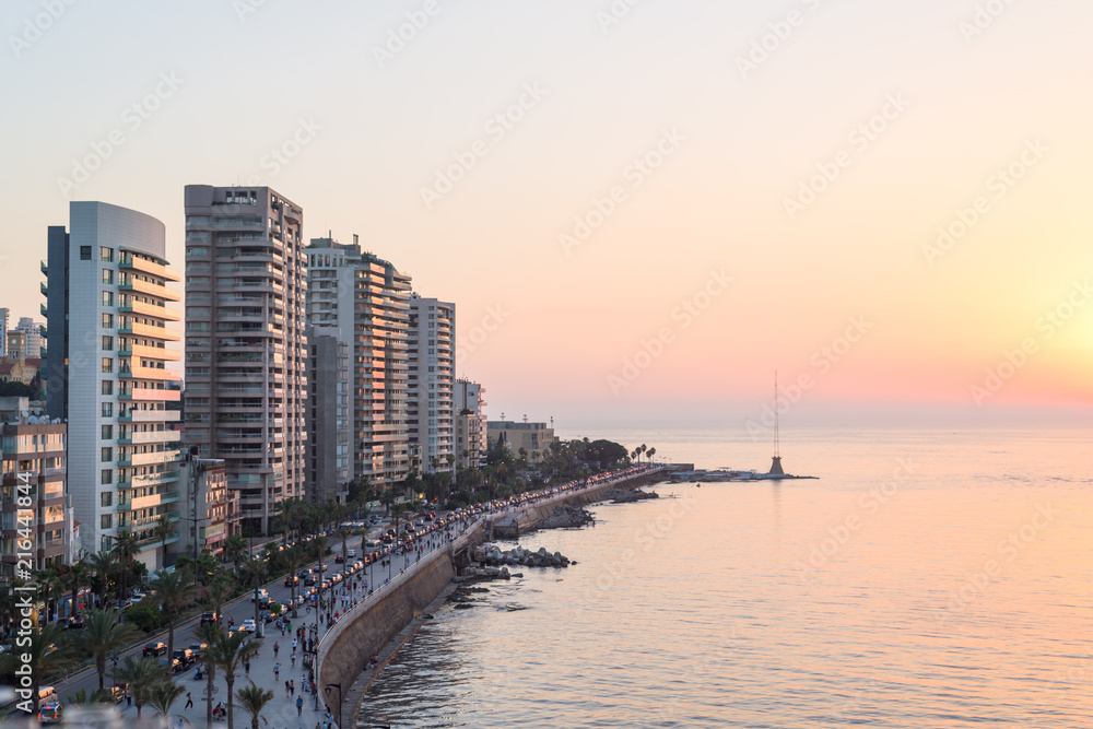 Fototapeta premium Beirut Lebanon city sea front at sunset, high rise residential buildings and pedestrian walkway along the Mediterranean sea, in Corniche, Lebanon