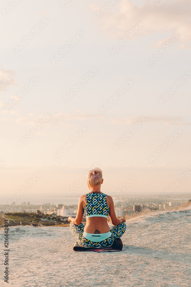 Fototapeta premium woman meditating in lotus position on the mountainside, yoga, sea view