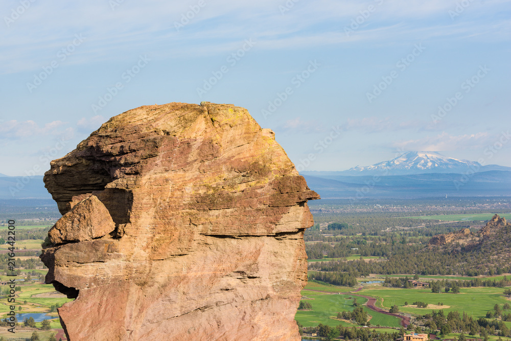 Rock column used for climbing in Smith Rock State Park, and Mount Jefferson volcano behind.