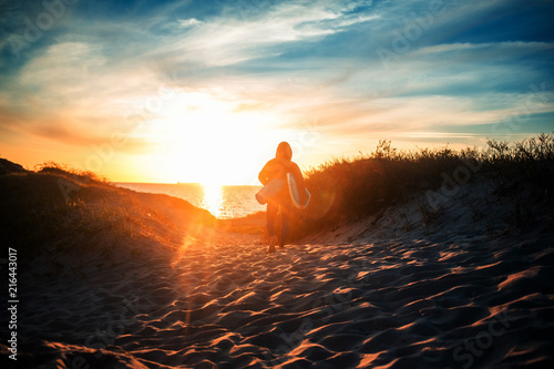 Sun surfer. A man is walking with a surf in his hands across the sea shore. photo