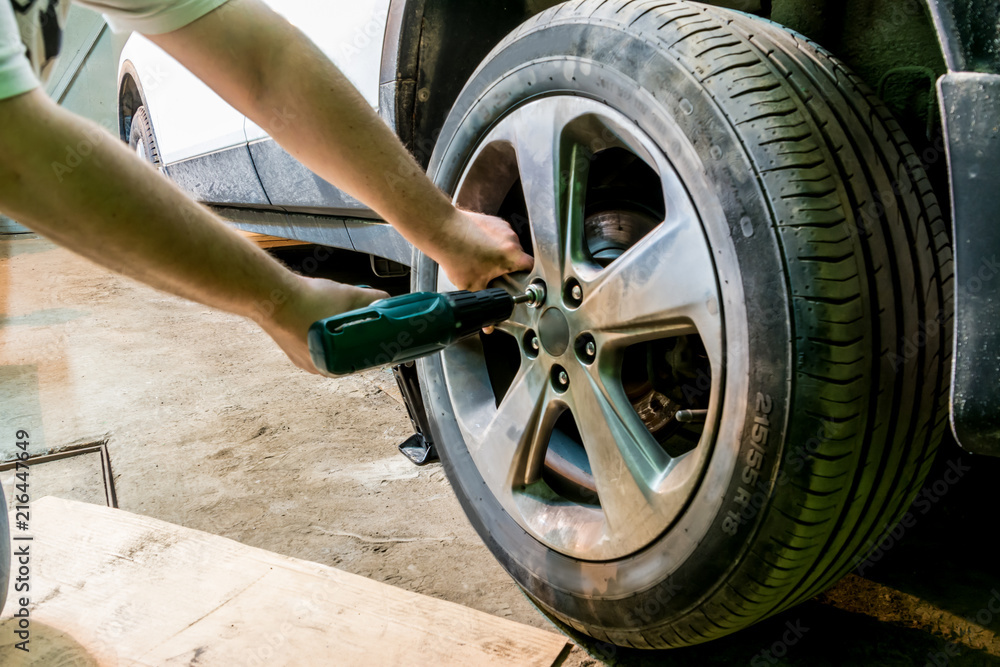 The mechanic unscrews the nuts on the wheel. Man exchanging tire. Tire service. Tire fitting.