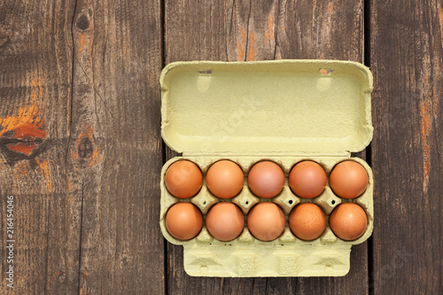 Overhead view of brown eggs in a cardboard box on wood