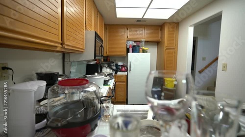 Dolly across messy condo kitchen with dirty dishes and clutter.   