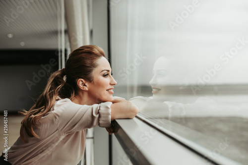 Side view happy woman dreaming while looking at window indoor. She having rest during labor
