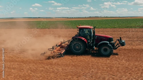 Aerial drone view of red tracor working in wheat field. Agriculture and environment in European Union. photo