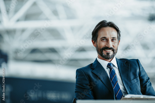 Portrait of beaming bearded male having job indoor. He looking at camera. Positive employer concept. Copy space photo
