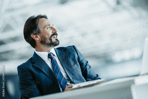 Low angle side view outgoing businessman situating at table during labor in office