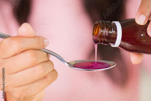 Papier peint Woman hand pouring medication or antipyretic syrup from bottle to spoon