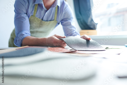Photos Close-up of craftsman working with pieces of leather at his workplace in worksho