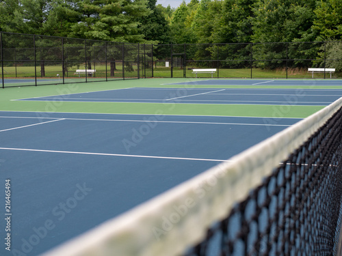 Close view of tennis court net with background courts in focus  © David Tran