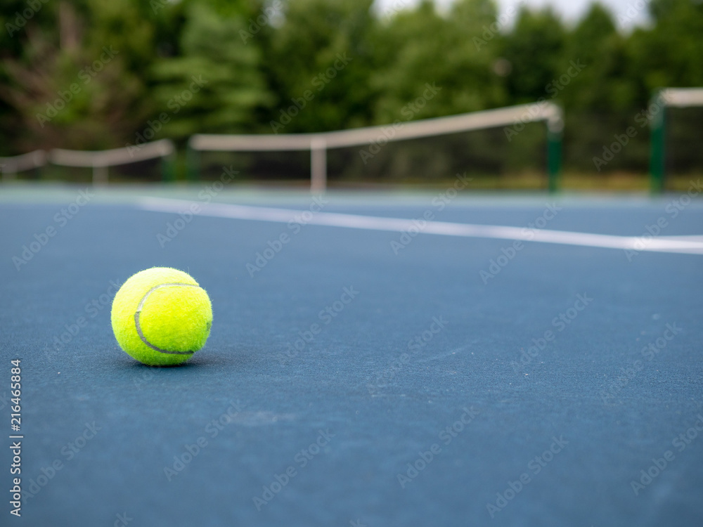 Green tennis ball sitting on court with copy space to the right