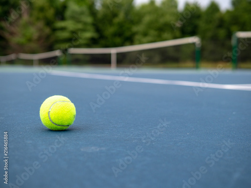 Green tennis ball sitting on court with copy space to the right