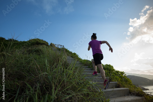 Woman running up on seaside mountain stairs