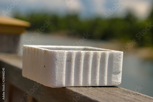A styrofoam bait worm container on a ledge next to a lake ready to be used for fishing. blurred background and isolated object with room for copy space photo