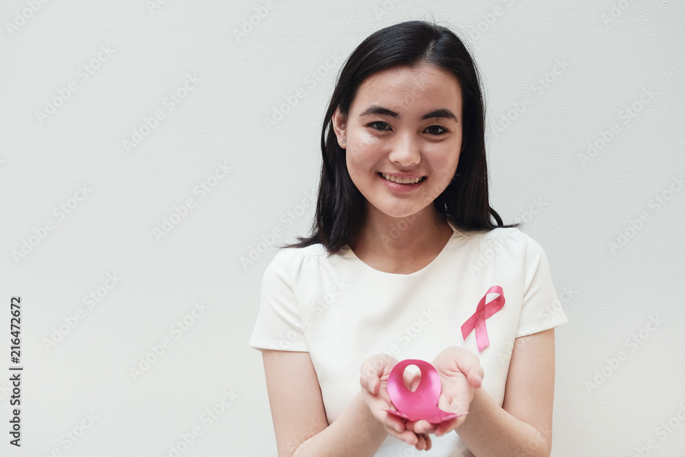 Asian young woman holding pink ribbon, breast cancer awareness, October pink concept Asian young woman holding pink ribbon, breast cancer awareness, October pink concept