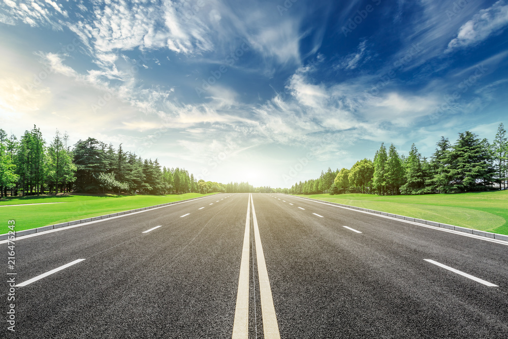 Asphalt road and green forest landscape under the blue sky