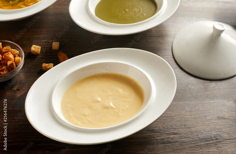 Close-up view of bowl of cheese cream soup on wooden table Close-up view of bowl of cheese cream soup on wooden table