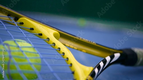 Close up of tennis equipment on the court. Sport, recreation concept. Yellow racket with a tennis ball in motion on a clay green blue court next to the white line with copy space and soft focus. photo