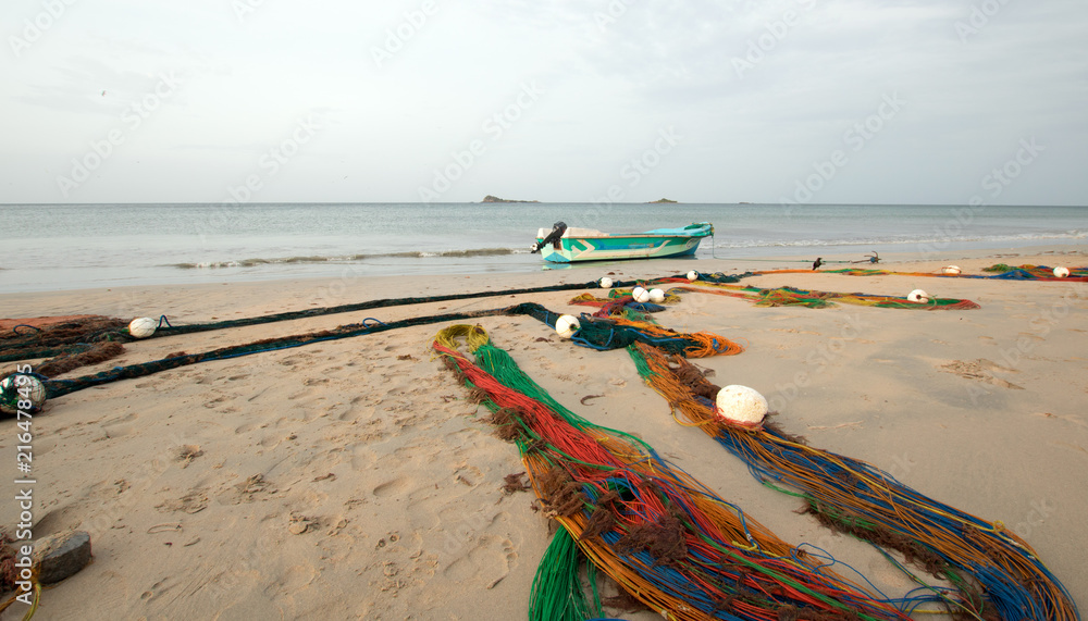 Small fishing boat next to fishing nets drying on Nilaveli beach