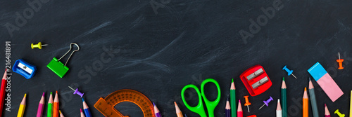 Back To School concept. School supplies on blackboard background, accessories for the schoolroom - pencils, notebooks, scissors, chalk, markers.
