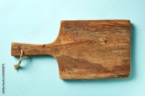 Wooden cutting board on blue background, from above