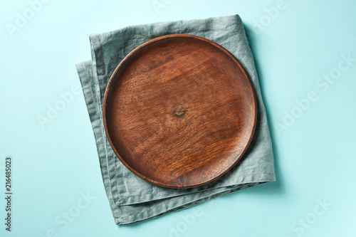 Wooden plate on blue background, from above