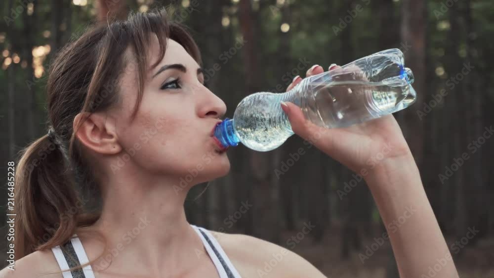 Close up of woman drinking water after sports training in fresh air Close up of woman drinking water after sports training in fresh air