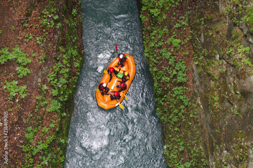 Un canoë orange avec six personnes dedans va dans les rapides