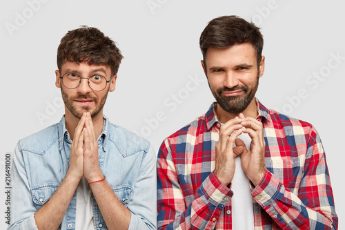 Attractive young clever male students with bristle, keeps hands together as have intention to do something, have intriguing expressions, look curiously at camera, isolated over white background