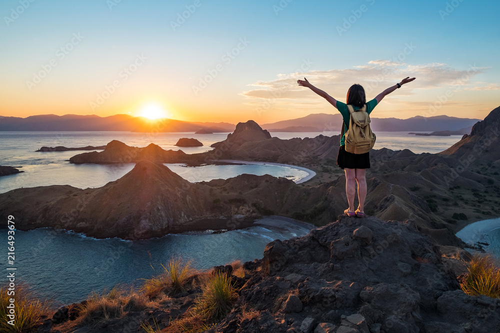 Fototapeta premium A woman standing on the peak of Padar Island in sunset time, Komodo Nation Park, Indonesia.