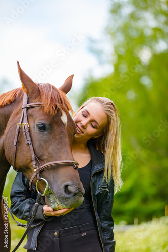 Young woman with her arabian horse standing in the field