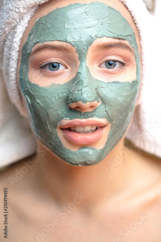 Beautiful woman with eyes closed and white clay facial mask on face isolated on white background