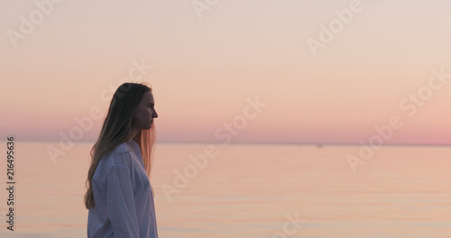 teenage girl standing on a beach at sunset