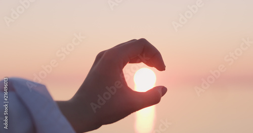 young female hand catches sun in her hand