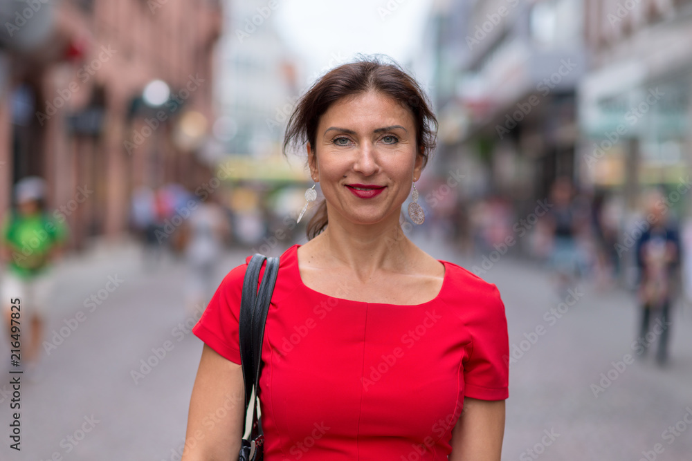 Woman wearing red dress and walking along road
