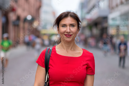 Woman wearing red dress and walking along road