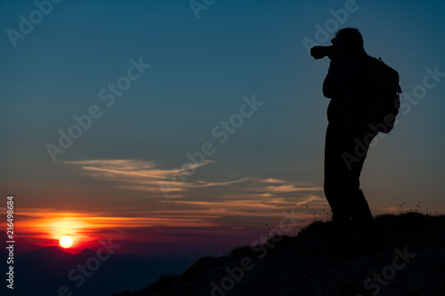 Photographing the sunset in the mountains. Photographer in silhouette