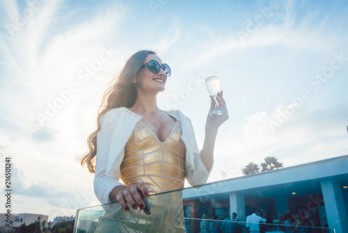 Canvas Print Woman having champagne at summer party with villa in the background